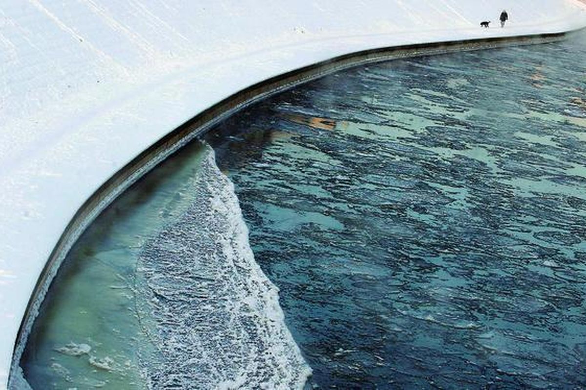 Seorang pria  berjalan bersama anjingnya di tepian Sungai Neris di Vilnius, Lituania, Selasa (31/1) pagi, saat suhu udara merosot hingga -23 derajat celsius. Udara dingin membekukan disertai salju melanda Eropa tengah dan timur, menyebabkan 36 orang tewas, memutus aliran listrik ke kota-kota, dan memacetkan lalu lintas.