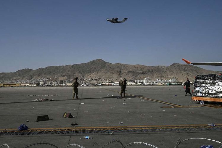 Tentara AS berjaga saat warga saling berebut untuk melarikan diri ke luar negeri, di Bandara Kabul, Afghanistan, Senin (16/8/2021). Bandara Kabul dilanda kekacauan ketika ribuan orang mencoba melarikan diri dari Taliban yang dilaporkan segera menguasai penuh Afghanistan.