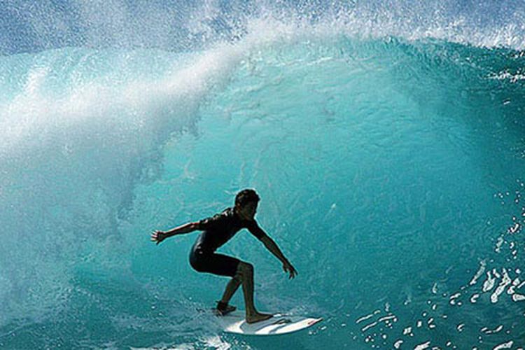 Surfer sedang melakukan surfing di pulau Panaitan, Taman Nasional Ujung Kulon, Banten.