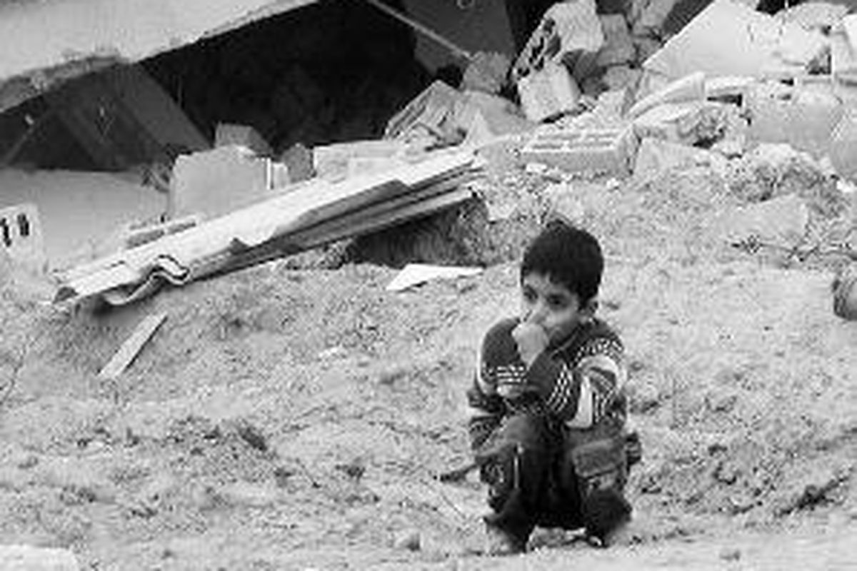 Mustafa, bocah lelaki berusia 5 tahun, Jumat (23/1), berjongkok di depan rumah orangtuanya di Bukit Jabaliya, Jabaliya Timur, Jalur Gaza, yang hancur dibom pesawat tempur Israel, F-16, pada 27 Desember 2008. Selama tiga minggu, pesawat tempur, helikopter, dan tank Israel memorakporandakan wilayah ini.