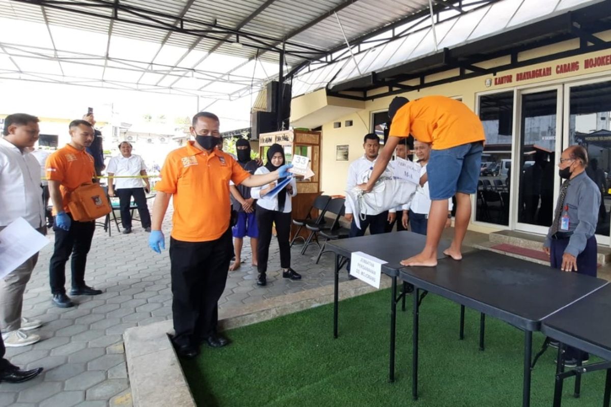 Dua pelaku pembunuhan terhadap AE, siswi SMP di Kabupaten Mojokerto, Jawa Timur, memeragakan adegan membuang jasad korban, saat rekonstruksi di Mapolres Mojokerto Kota, Senin (19/6/2023.