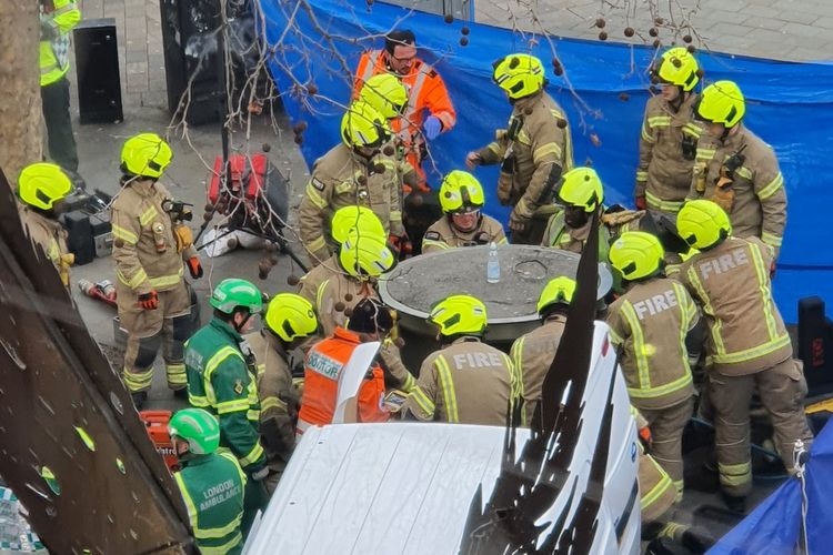 Tim gabungan pemadam kebakaran, polisi, paramedis, dan kru ambulans udara berupaya menyelamatkan pria yang tertimpa toilet umum teleskopik di London, Inggris, Jumat (27/1/2023). Pria tersebut dinyatakan tewas.