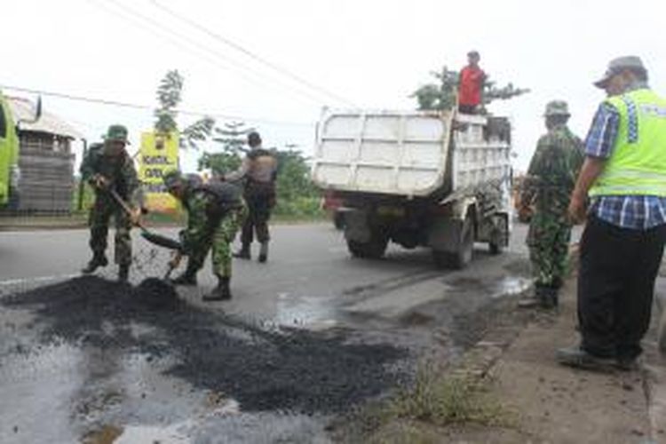 Personil TNI AD membantu pekerja perbaikan jalan di jalur utama pantura Bulakamba, Brebes, Jawa Tengah, Minggu (9/2/2014).