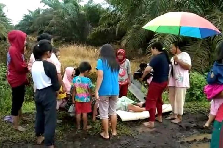 Sejumlah ibu-ibu membantu Wahyuni (38) saat melahirkan bayi di jalan berlumpur di Kepenghuluan Sungai Sanggam, Kecamatan Limau Kapas, Kabupaten Rohil, Riau, Kamis (24/9/2020).