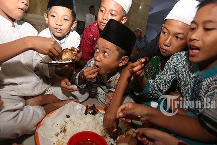 sejumlah anak-anak menyantap hidangan berbuka puasa dalam tradisi megibung saat bulan Ramadan di Masjid Al-Muhajirin, Kampung Islam Kepaon, Denpasar