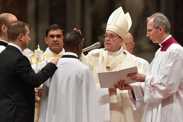 Paus Fransiskus membaptis John Ogah (tengah) dalam misa Malam Paskah di Basilika Santo Petrus, Sabtu (31/3/2018) di Vatikan. (AFP/Andreas Solaro)