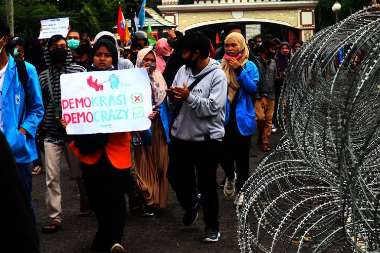 Ratusan mahasiswa melewati pagar kawat yang digunakan untuk melindungi gerbang kantor DPRD Provinsi Jambi saat aksi tolak omnibus law UU Cipta Kerja, pada Senin (12/10/2020)