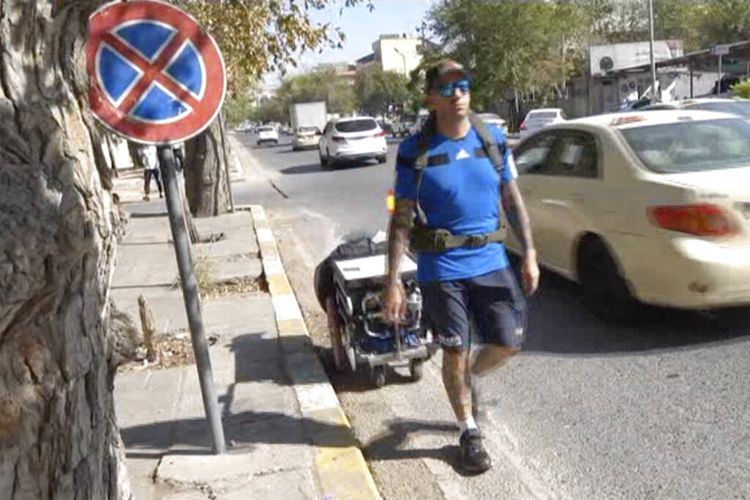 Dalam gambar yang diambil dari video ini, Santiago Sánchez, 41 tahun, seorang pria Spanyol yang mendokumentasikan perjalanannya dengan berjalan kaki dari Madrid ke Doha untuk Piala Dunia FIFA 2022 membawa sebuah koper dalam gerobak beroda, di Sulaymaniyah, Irak, 9 September 2022.