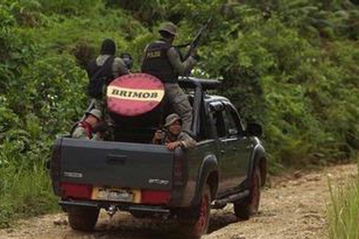 Polisi dengan senjata laras panjang naik di atas mobil bak terbuka melewati kebun kakao menuju Dusun Tamanjeka, Desa Masani, Kecamatan Poso Pesisir, Kabupaten Poso, Sulawesi Tengah, Selasa (6/11/2012). Sebanyak 300 polisi dan TNI disiagakan terkait ditemukannya kamp pelatihan dan senjata rakitan di lereng Gunung Kalora.