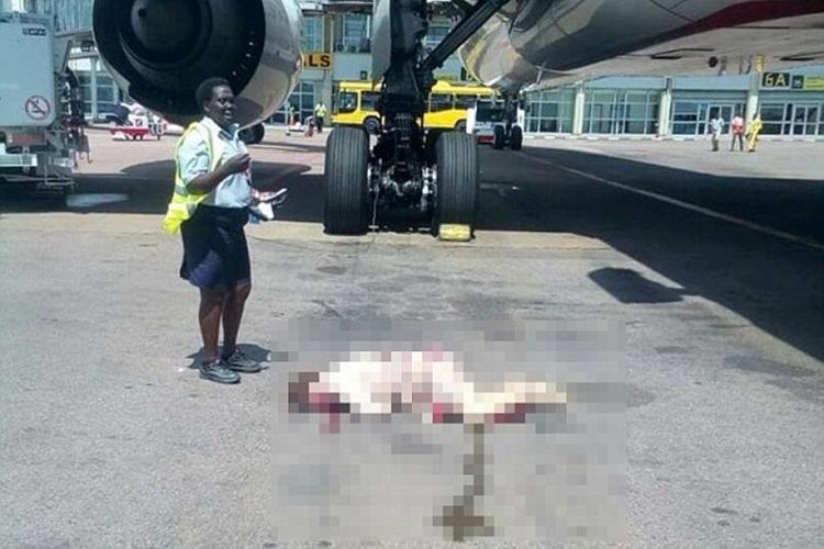 Seorang petugas bandara internasional Entebbe, Uganda berdiri di dekat seorang pramugari maskapai penerbangan Emirates yang terluka setelah membuka pintu darurat dan melompat.