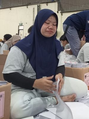 Seorang petugas sortir-lipat surat suara Pemilu 2024, Siti Nur Aini sedang duduk melipat surat suara di Gudang Logistik KPU, Klapanunggal, Kabupaten Bogor, Jawa Barat, Senin (15/1/2024).