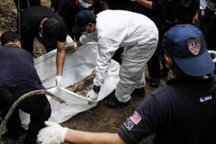 Tim forensik Kepolisian Kerajaan Malaysia membongkar kuburan massal di hutan Bukit Wang Burma di Perlis, negara bagian utara Malaysia, yang berbatasan dengan Thailand, 26 Mei 2015.