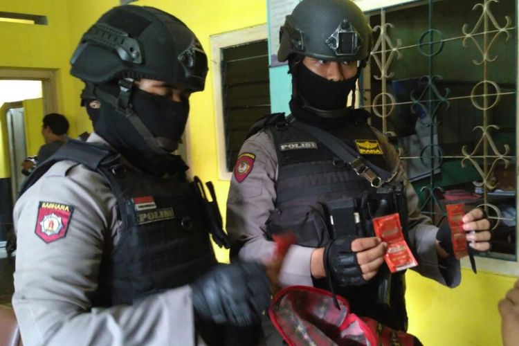 Dua personel Polresta Surakarta menunjukkan kondom dari hasil operasi kepolisian di sebuah hotel kelas malati di Solo, Jawa Tengah, Kamis (28/12/2017).