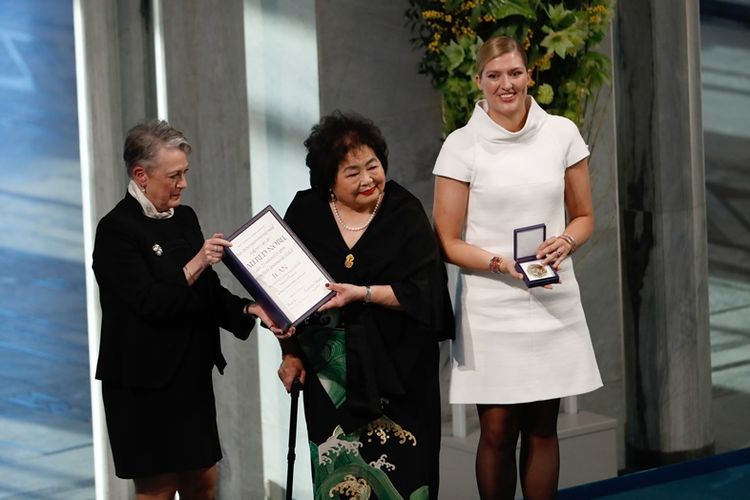 Berit Reiss-Andersen (kiri), Ketua Komite Nobel Norwegia, menyerahkan Hadiah Nobel Perdamaian 2017 kepada Beatrice Fihn (kanan), pemimpin ICAN, dan korban bom nuklir Hiroshima Setsuko Thurlow (tengah) pada acara penghargaan Hadiah Nobel Perdamaian 2017 di balai kota di Oslo, Norwegia, Minggu (10/11/2017). (AFP/Odd Andersen)