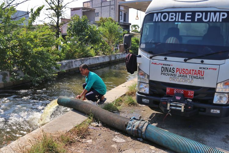 Mobil pompa milik Dinas Pusdataru Provinsi Jateng sedang mengalirkan air hasil penyedotan rob ke sungai.