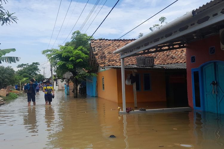 Warga menerjang banjir di Desa Karangligar Kecamatan Telukjambe Barat, Karawang, Jawa Barat, Selasa (20/5/2025).
