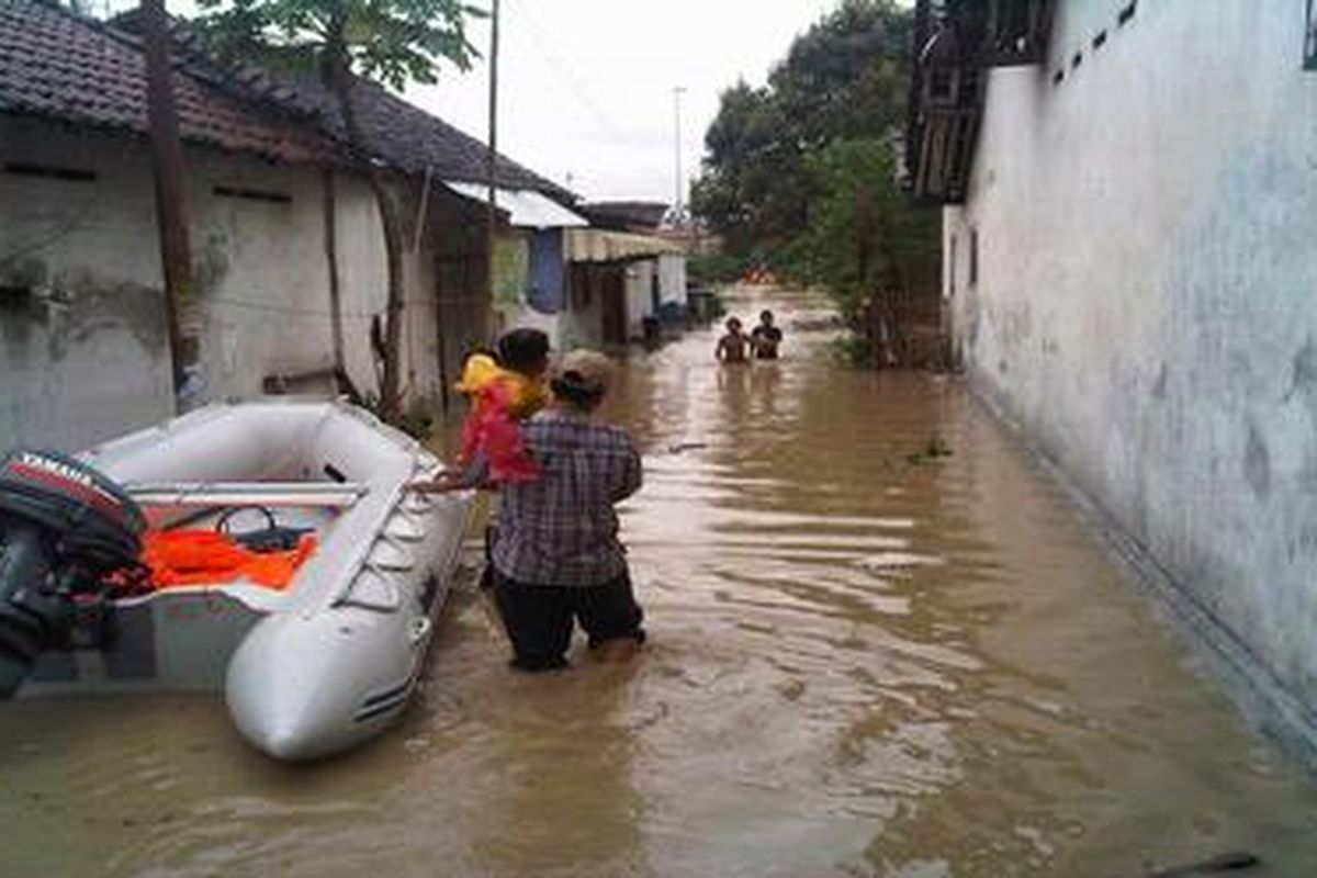 Warga Desa Maribaya, Kecamatan Kramat, Kabupaten Tegal, Jawa Tengah, melintasi genangan banjir di wilayahnya, Sabtu (29/12/2012).