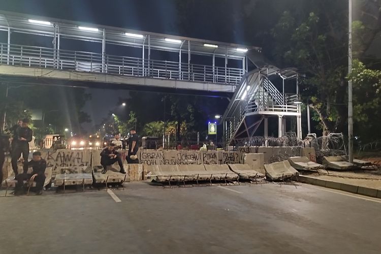 Beton pembatas jalan jatuh dan dicoret-coret saat demo evaluasi sembilan tahun pemerintahan Presiden Joko Widodo di Patung Kuda, Gambir, Jakarta Pusat, Jumat (20/10/2023). (KOMPAS.com/XENA OLIVIA)