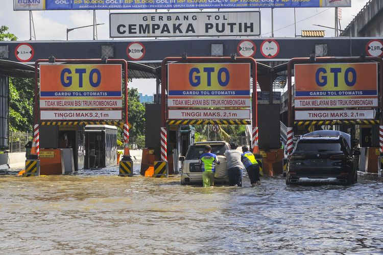Sejumlah petugas membantu mendorong mobil yang mogok akibat banjir di gerbang tol Cempaka Putih, Jakarta Pusat, Minggu (23/2/2020). Menurut petugas banjir merendam pintu tol dari jam 03.00 WIB akibat luapan air dari waduk ria rio. ANTARA FOTO/ Fakhri Hermansyah/foc.