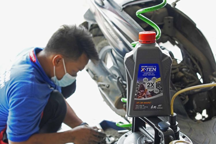 Seorang mekanik sedang melakukan ganti oli motor dengan produk oli motor X-Ten untuk motor harian dengan daya tahan tinggi.