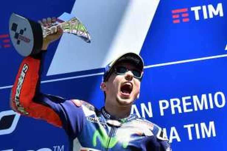 Pebalap Movistar Yamaha asal Spanyol, Jorge Lorenzo, mengangkat trofi juara setelah finis di urutan pertama pada balapan GP Italia di Sirkuit Mugello, Minggu (22/5/2016).