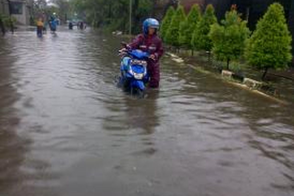 Salah satu pengendara terpaksa menuntun motornya lantaran banjir yang menggenangi jalan Peternakan II, Kapuk, Jakarta Barat, Senin (9/2/2015)