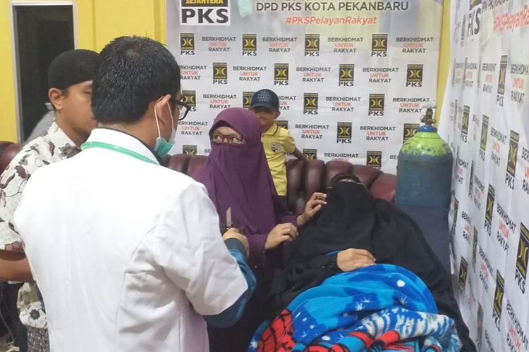 Dokter Rio Hendra memeriksa kesehatan seorang wanita yang pingsan karena kebanyakan menghirup asap di posko kesehatan Kantor DPW PKS Riau di Pekanbaru, Riau, Rabu (18/9/2019).