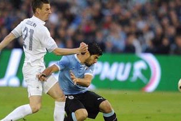 Striker Uruguay, Luis Suarez (kanan), berebut bola dengan bek Perancis, Laurent Koscielny pada laga persahabatan di Stadion Centenario, Uruguay, Rabu atau Kamis (6/6/2013) dini hari WIB. pada laga itu, Suarez mencetak gol dan memastikan Uruguay menang 1-0.