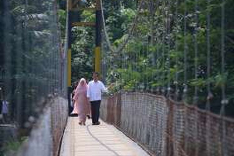 Presiden Joko Widodo dan Ibu Negara Iriana meniti jembatan gantung baru di Kampung Ranca Garut, Sangiang Tanjung, Kalanganyar, Lebak, Banten, Senin (4/7/2016).