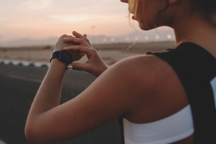 Ilustrasi pelari menggunakan jam tangan pintar dan aplikasi pencatat lari.