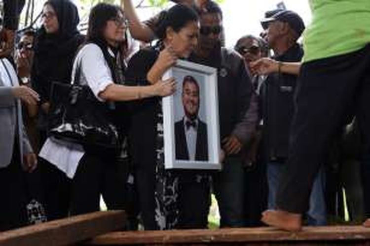 Ibunda Mike Mohede, Amin Yudhayani, membawa foto putranya dalam prosesi pemakaman di TPU Tanah Kusir, Jakarta Selatan, Selasa (2/8/2016).