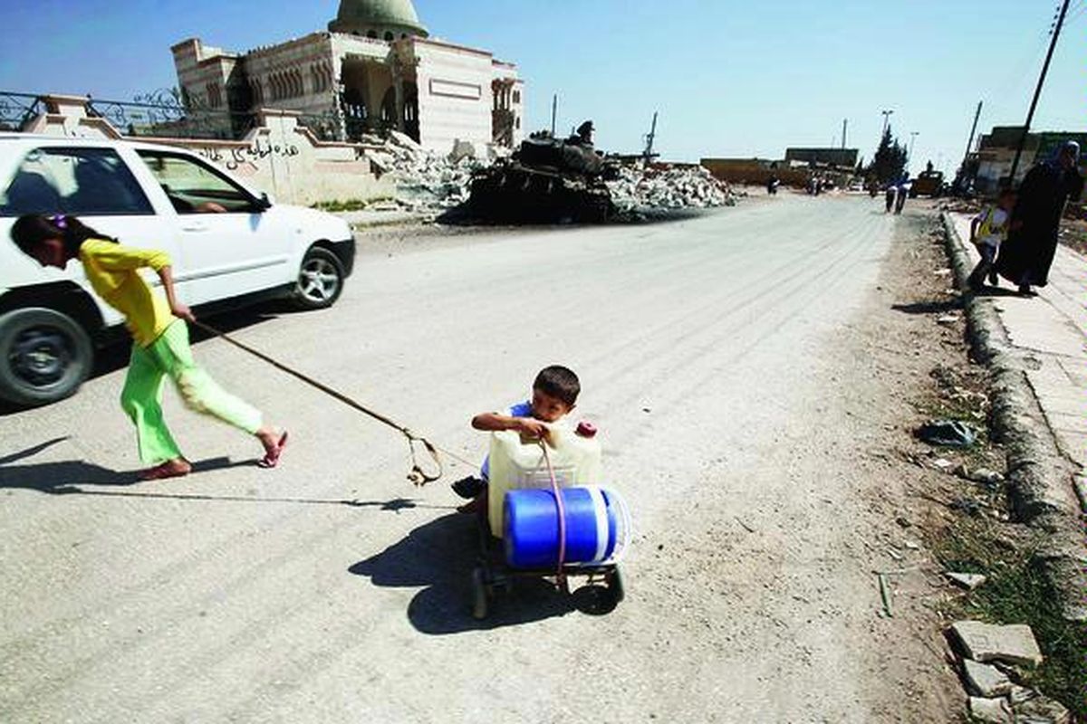 Seorang anak perempuan Suriah menarik troli berisi jeriken kosong yang dinaiki adik laki-lakinya dalam perjalanan mengambil air bersih di Azaz di pinggir kota Aleppo, Suriah, Selasa (28/8). Kehidupan sehari-hari warga Suriah makin berat seiring terus berlangsungnya konflik bersenjata antara pemerintah dan oposisi.