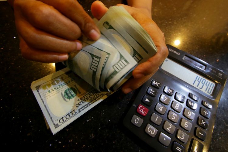 Petugas menghitung uang pecahan dolar Amerika Serikat di gerai penukaran mata uang asing di Jakarta. 