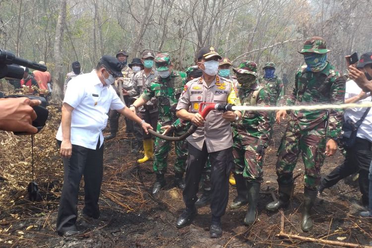 Kapolda Riau Irjen Pol Widodo Eko Prihastopo turut mencoba mematikan api kebakaran lahan gambut saat meninjau lokasi karhutla bersama Wakil Gubernur Riau Edy Natar Nasution dan Danlanud Roesmin Nurjadin Pekanbaru Marsma TNI Sonny Aprianto Moningka di Jalan Kampung Baru, Kelurahan Terkul, Kecamatan Rupat, Kabupaten Bengkalis, Riau, Rabu (27/2/2019).