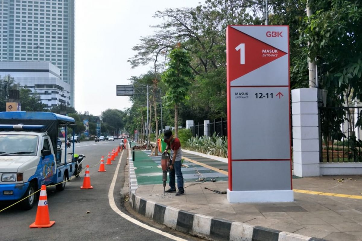 Pekerja PT Adhi Karya membongkar ujung trotoar di Jalan Pintu 1 Senayan, Jakarta Pusat, untuk membuat ramp jalur sepeda, Jumat (3/8/2018).