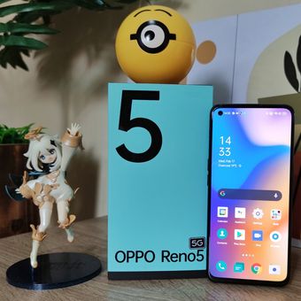 Oppo Reno5 5G bersama kotak penjualannya. Sekilas, desain kotak kemasan ponsel ini memang berbeda dengan pendahulunya, Reno4. Namun, tampilannya masih seirama dengan Reno5. Alih-alih hijau pinus pekat, kotak penjualan Reno5 5G kini dilapisi dengan warna hijau toska yang adem di mata. Ponsel ini juga terasa ringan dan nyaman digenggam dan memiliki layar yang cukup lega.
