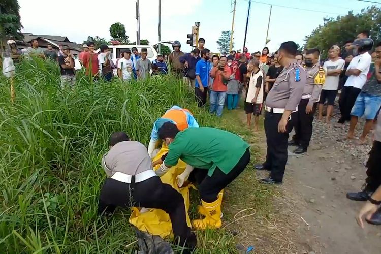 Polisi dan petugas medis, mengevakuasi korban meninggal dunia akibat tersambar kereta api di Tulungagung Jawa Timur, Senin (20/06/2022).