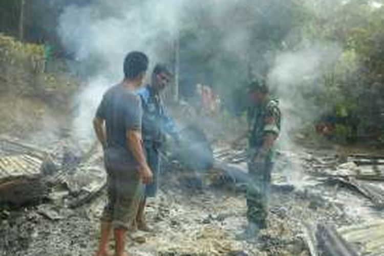 Seorang anggota Koramil dan warga menunjukkan jasad ibu dan balitanya yang sudah gosong di tengah puing rumahnya Dusun Tea, Desa Mattirowalie, Kecamatan Libureng, Kabupaten Bone, Sulawesi Selatan, sebelum akhirnya polisi tiba dan mengevakuasi jasad korban, Jumat (21/10/2016).