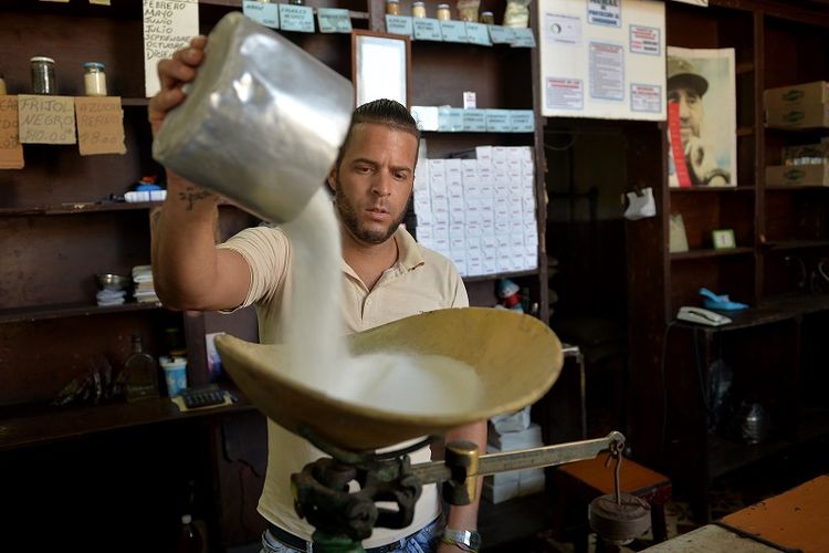 Seorang pria tengah menakar gula di sebuah toko di Havana, Kuba.