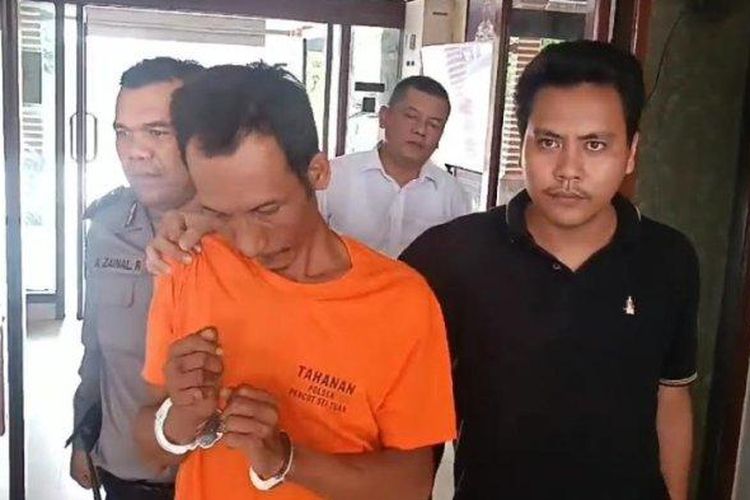 Tampang Sulaiman Purba, pembakar wanita pemilik rumah makan, Herlinda Gurusinga, saat digiring oleh petugas memasuki sel tahanan di Mapolsek Medan Tembung, Medan, Senin (20/5/2024). 
