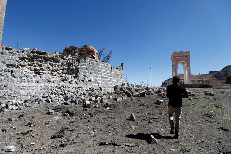 Salah seorang warga Yaman berjalan di dekat lokasi reruntuhan akibat serangan udara yang dilancarkan koalisi pimpinan Arab Saudi di kota Aser, selatan ibu kota Sanaa, pada Senin (25/12/2017).
