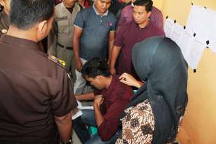 Seorang pelanggar syariat islam sedang membuka pakaiannya satu persatu saat jeda per 20 kali cambukan pertama, Kamis (26/6/2016). Pria berinisial DS (35 tahun) ini ternyata kedapatan mengenakan pakaian berlapis serta menempelkan busa dibagian belakangnya untuk menghindari rasa sakit akibat cambukan algojo.