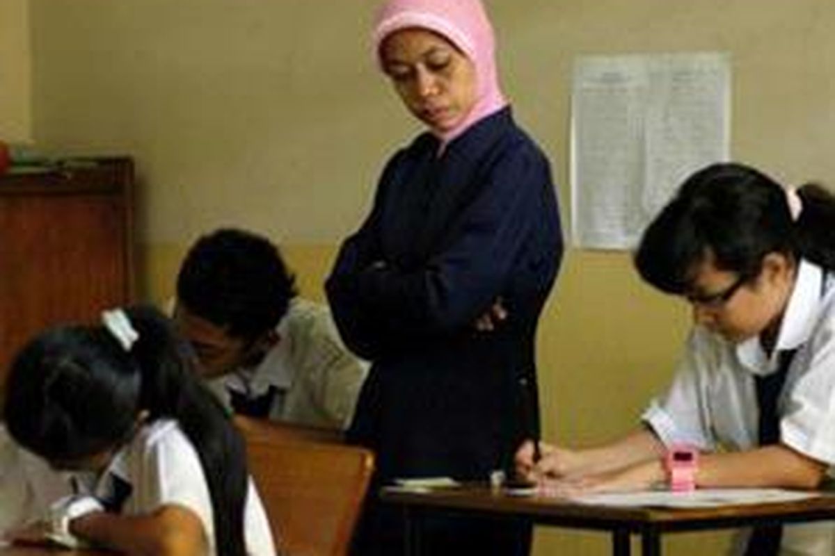 Seorang pengawas tengah mengawasi jalannya ujian nasional hari pertama di Sekolah Lanjutan Pertama Luar Biasa Yayasan Santi Rama, Jakarta, Senin (5/5). Sebanyak 22 siswa penyandang cacat tunarungu sekolah ini mengikuti ujian nasional. 