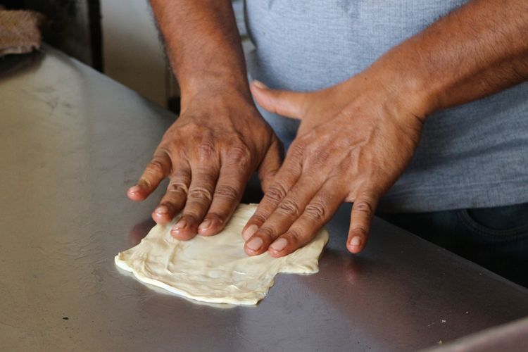 Mohammad Yasin sang pemilik masih terjun langsung menangani adonan roti prata untuk dipanggang