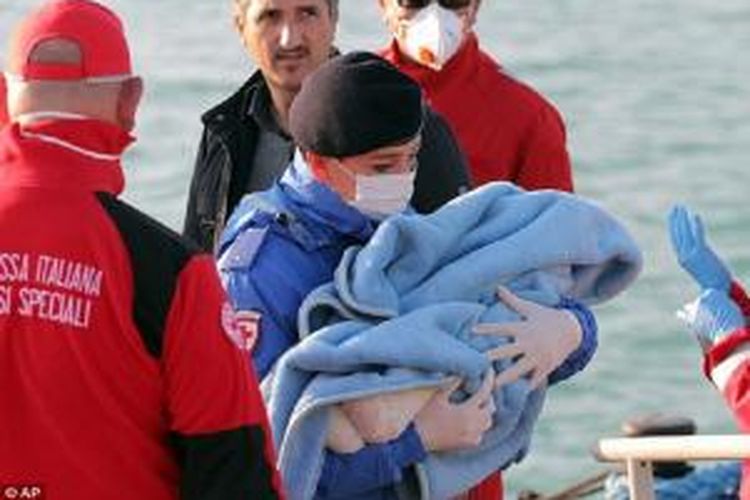 Seorang relawan Palang Merah membawa bayi yang terbungkus selimut setelah para imigran turun di pelabuhan Sisilia Porto Empedocle, Italia, Senin (13/4/2015).