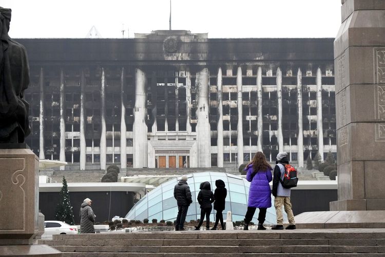 Orang-orang melihat gedung balai kota di alun-alun pusat yang diblokir oleh pasukan dan polisi Kazakhstan di Almaty, Kazakhstan, Selasa, 11 Januari 2022. 