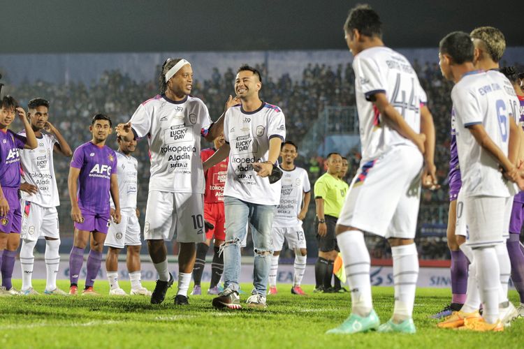 Mantan pesepak bola dunia asal Brazil Ronaldinho (tengah) berjalan dengan Chairman RANS Nusantara FC Raffi Ahmad saat membuka pertandingan Trofeo Ronaldinho di Stadion Kanjuruhan, Malang, Jawa Timur, Minggu (26/6/2022). Ronaldinho memperkuat tim RANS Nusantara FC dalam trofeo yang diikuti Arema FC dan Persik Kediri dalam rangkaian kunjungannya di Malang. ANTARA FOTO/Rizal Hanafi/Ds/aww.