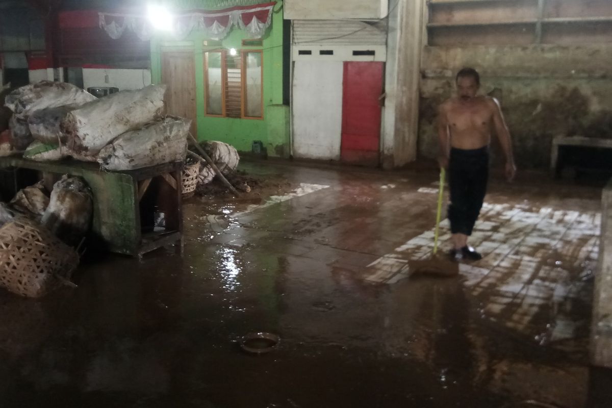 Seorang pedagang di Pasar Induk Jambu Dua Bogor sedang membersihkan material lumpur, Jumat (26/4/2019).