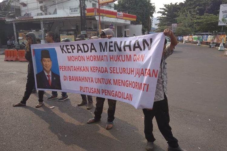 Spanduk berisi kalimat protes lengkap dengan foto wajah Menhan Prabowo Subianto yang dibawa oleh ahli waris pemilik sah lahan Tol Jatikarya. Protes dilakukan karena uang ganti rugi lahan mereka tak kunjung cair.