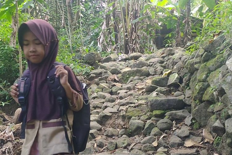 Dewi Septiani (12) Pedukuhan Watu Belah, Kalurahan Sidomulyo, Kapanewon Pengasih, Kabupaten Kulon Progo, Daerah Istimewa Yogyakarta. Ia dan keluarganya tinggal di kampung terpencil di Watu Belah.